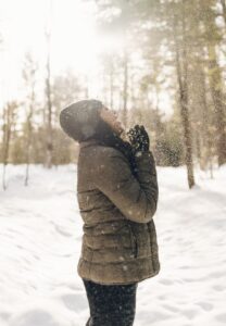 woman standing in the woods admiring snowfall